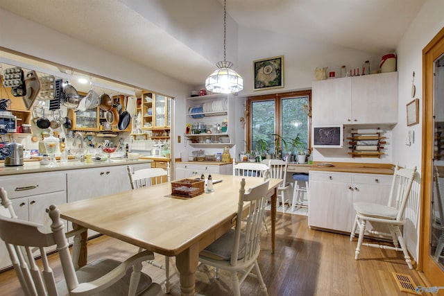 dining area featuring lofted ceiling, bar area, and light wood-type flooring