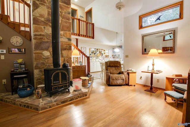 living room featuring a high ceiling, hardwood / wood-style flooring, and a wood stove