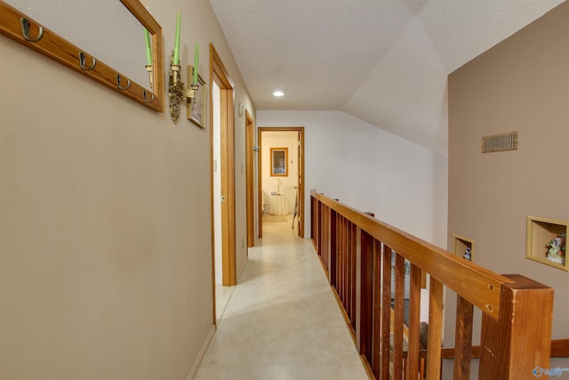 hall with a textured ceiling, lofted ceiling, and light colored carpet