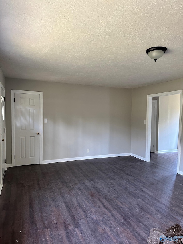 spare room featuring a textured ceiling and dark hardwood / wood-style floors