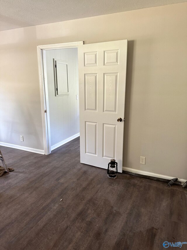 spare room with a textured ceiling and dark hardwood / wood-style flooring