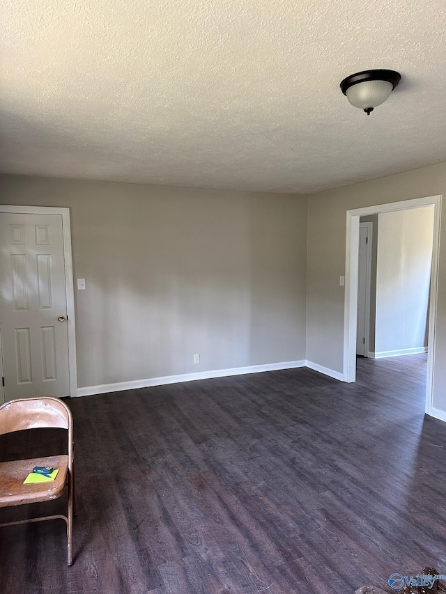 spare room with a textured ceiling and dark hardwood / wood-style floors