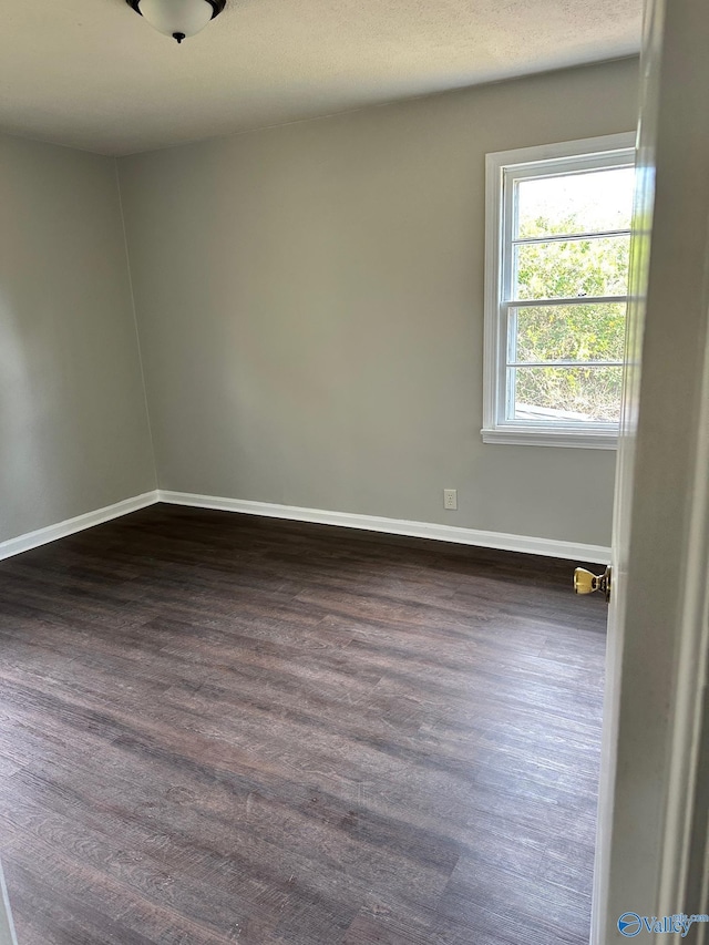 spare room featuring a textured ceiling and dark hardwood / wood-style flooring