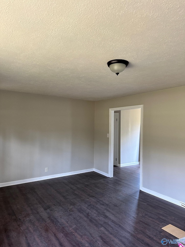 spare room featuring dark hardwood / wood-style floors and a textured ceiling