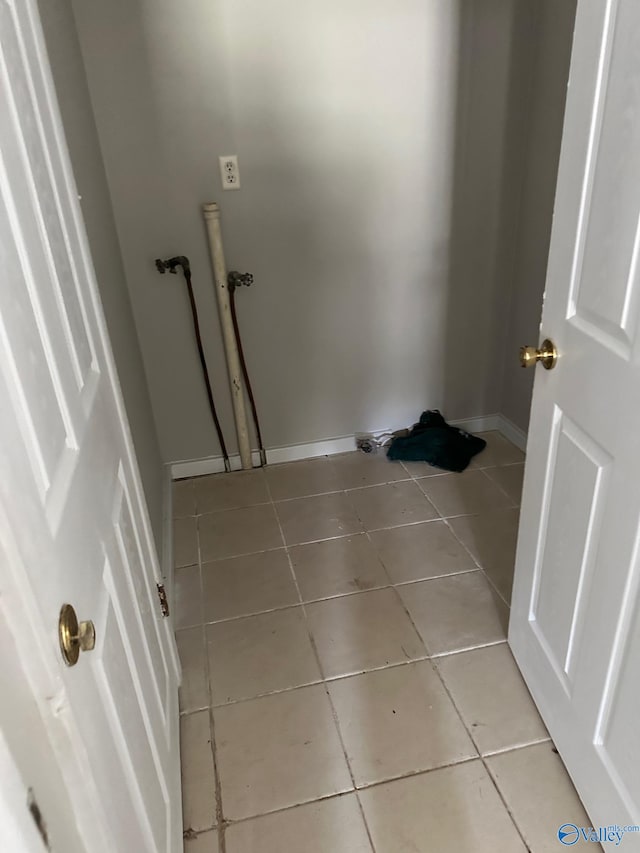 clothes washing area with light tile patterned floors