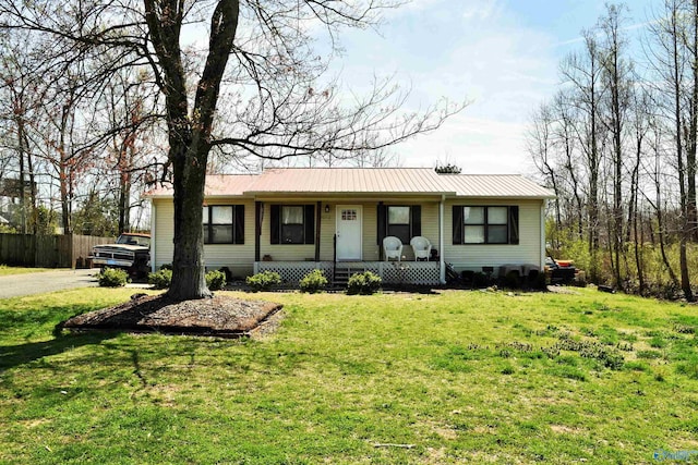 single story home featuring metal roof, a porch, a front yard, and fence
