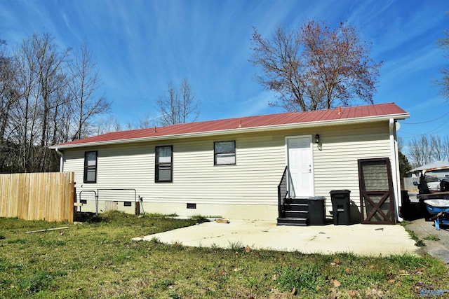 rear view of house with crawl space, fence, a lawn, and metal roof