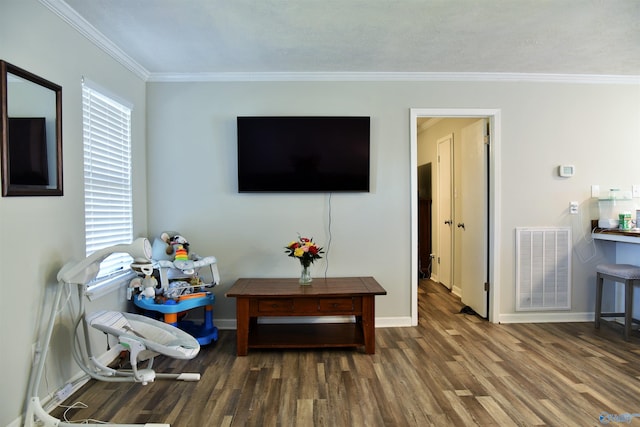 living area featuring visible vents, baseboards, wood finished floors, and ornamental molding