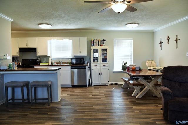 kitchen with under cabinet range hood, dark countertops, black appliances, and a wealth of natural light