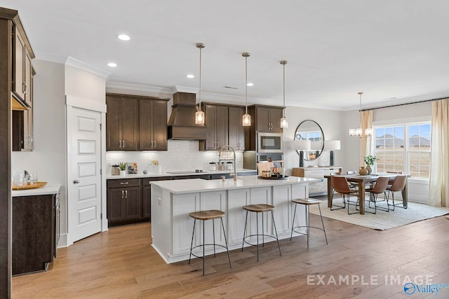 kitchen with pendant lighting, custom range hood, light hardwood / wood-style floors, black electric cooktop, and built in microwave