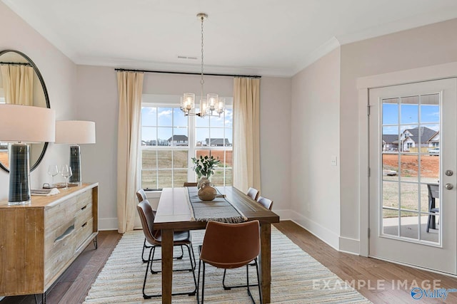 dining room featuring crown molding, dark hardwood / wood-style floors, a wealth of natural light, and a notable chandelier