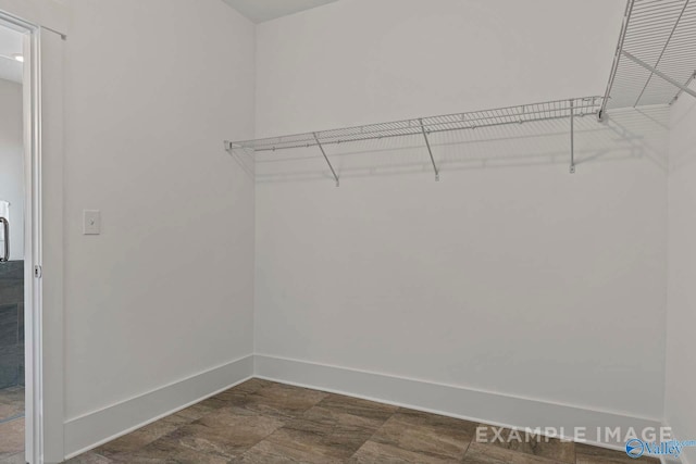 walk in closet featuring stone finish floor