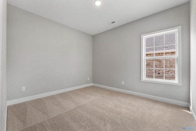 spare room featuring carpet, visible vents, and baseboards