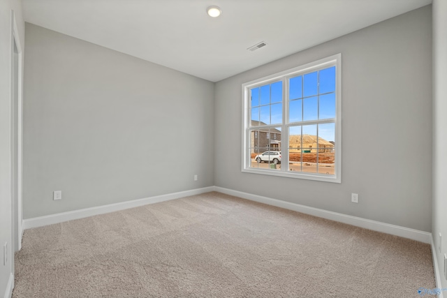 empty room with carpet floors, visible vents, and baseboards