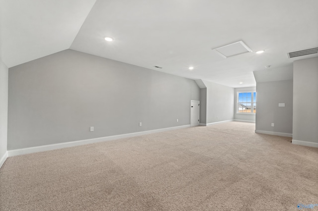 additional living space featuring light carpet, attic access, visible vents, baseboards, and lofted ceiling