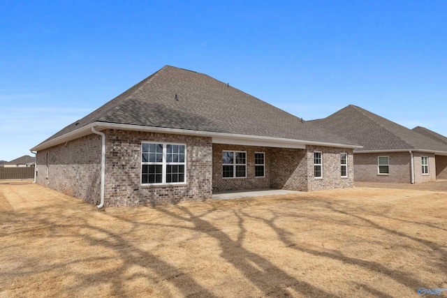 back of property featuring a shingled roof, a patio, and brick siding