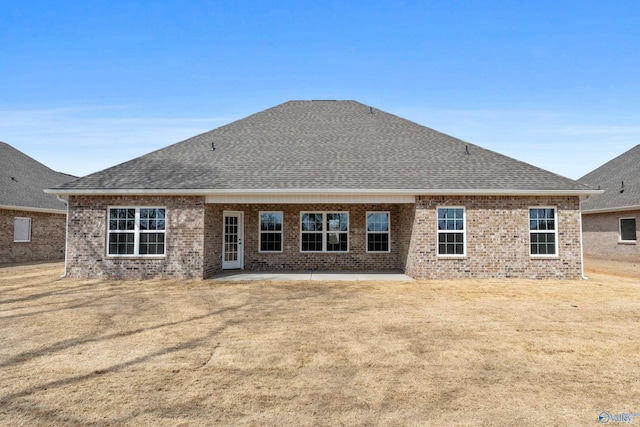 rear view of property featuring a patio, a shingled roof, and brick siding