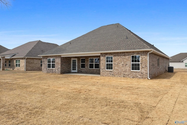 back of property with roof with shingles, cooling unit, and brick siding