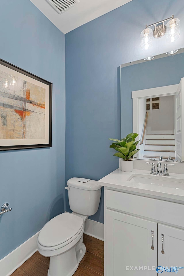 half bathroom with toilet, wood finished floors, visible vents, and baseboards