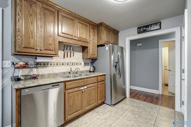 kitchen with appliances with stainless steel finishes, sink, light tile patterned floors, and decorative backsplash