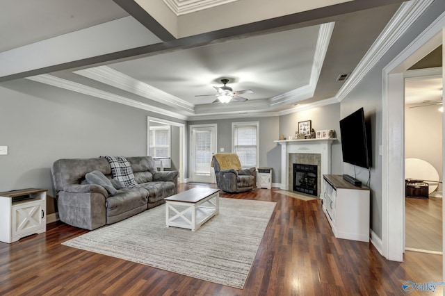 living room featuring crown molding, a tile fireplace, ceiling fan, dark hardwood / wood-style flooring, and a raised ceiling