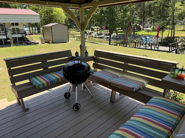 wooden deck featuring a shed, a lawn, and a water view