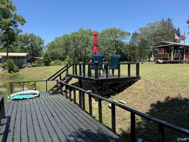 wooden terrace with a water view and a lawn