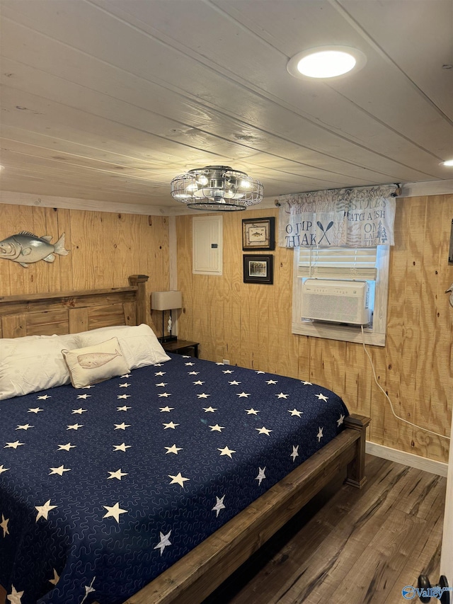 bedroom featuring cooling unit, hardwood / wood-style floors, wooden walls, and electric panel