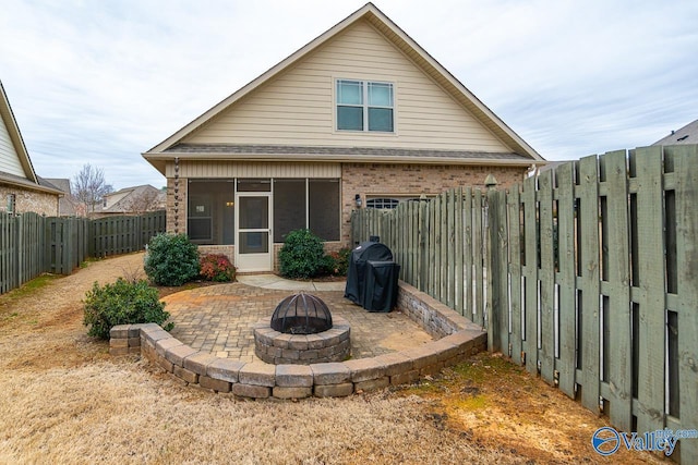 9 Leyland Dr SW, Huntsville, AL 35824 - rear view of property featuring a patio, an outdoor fire pit, a fenced backyard, brick siding, and a sunroom