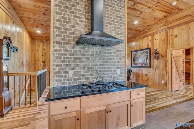 kitchen featuring wood ceiling, light hardwood / wood-style floors, wall chimney exhaust hood, black gas stovetop, and light brown cabinets