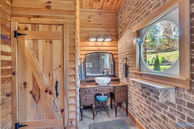 bathroom with vanity, wood walls, and brick wall