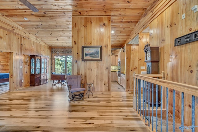 hallway featuring light hardwood / wood-style floors, a chandelier, wooden walls, and wooden ceiling