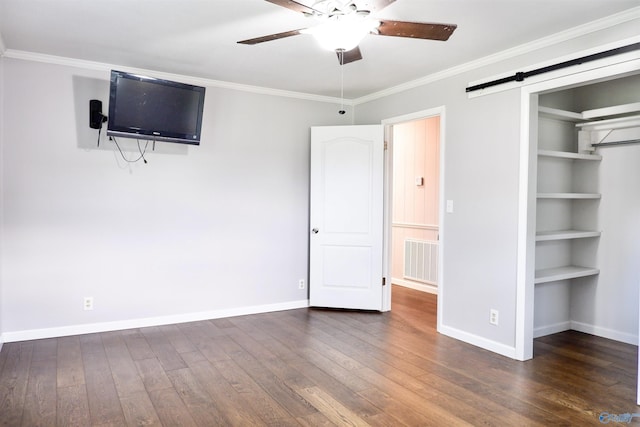 unfurnished bedroom featuring a barn door, ornamental molding, baseboards, and hardwood / wood-style floors