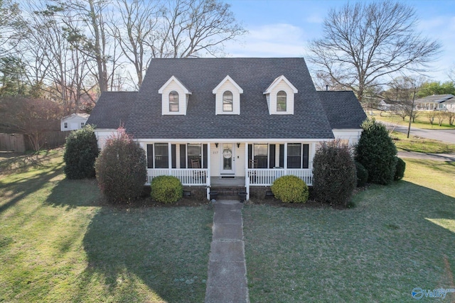 cape cod-style house with a shingled roof, a porch, and a front yard