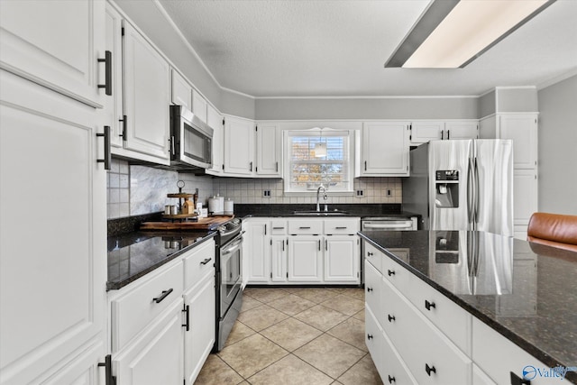 kitchen with white cabinetry, a sink, stainless steel appliances, and tasteful backsplash