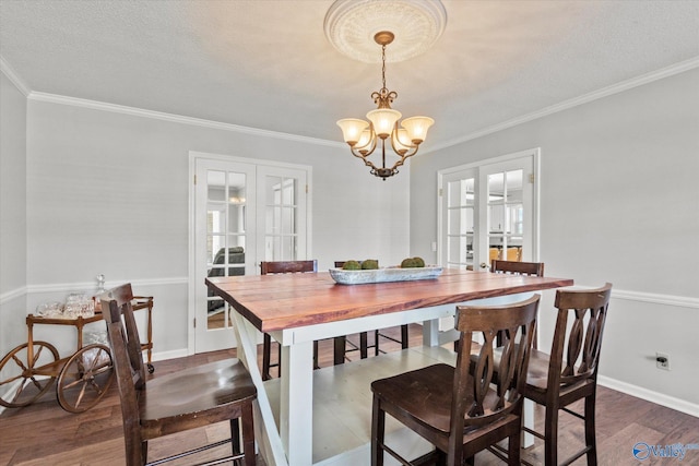dining area featuring french doors, dark wood-style floors, a chandelier, and crown molding