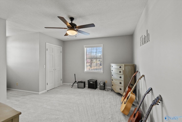 interior space with carpet flooring, a textured ceiling, baseboards, and ceiling fan