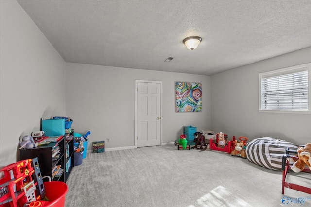 recreation room featuring baseboards, a textured ceiling, visible vents, and carpet