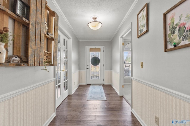 foyer with a wainscoted wall, crown molding, french doors, a textured ceiling, and dark wood-style flooring
