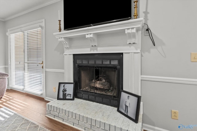 interior details featuring baseboards, a fireplace, wood finished floors, and ornamental molding