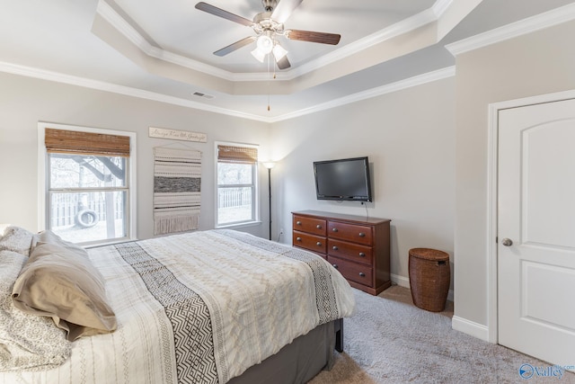 carpeted bedroom featuring ceiling fan, ornamental molding, multiple windows, and a tray ceiling