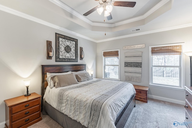 bedroom featuring ceiling fan, light colored carpet, ornamental molding, and a tray ceiling