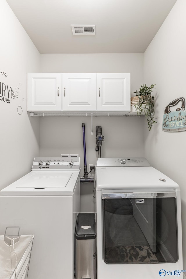 laundry room featuring washer and clothes dryer and cabinets