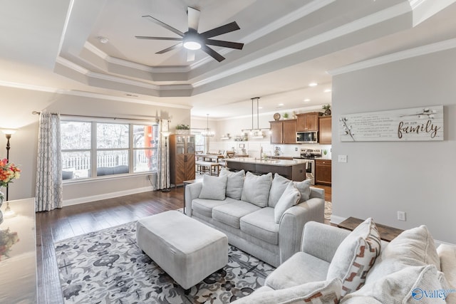 living room featuring a tray ceiling, ceiling fan, dark hardwood / wood-style flooring, and ornamental molding