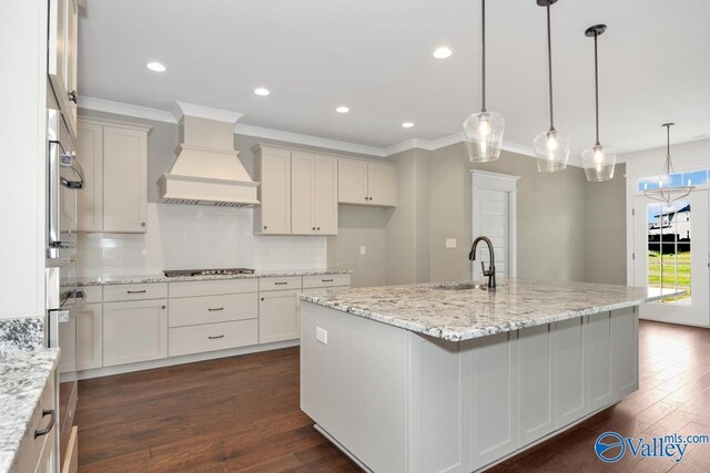 kitchen with a barn door, stainless steel appliances, dark hardwood / wood-style floors, premium range hood, and tasteful backsplash