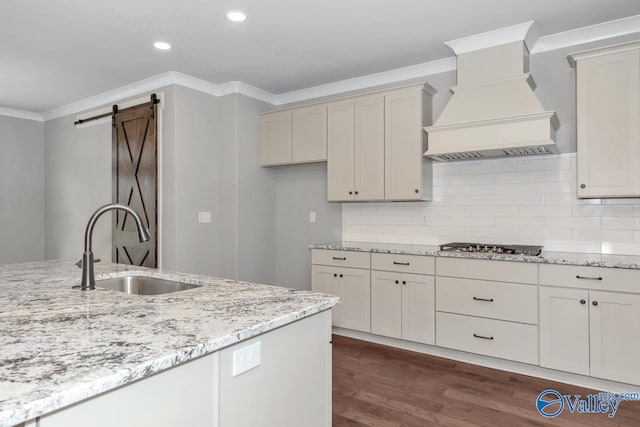 kitchen with decorative backsplash, custom range hood, ornamental molding, dark hardwood / wood-style floors, and a barn door