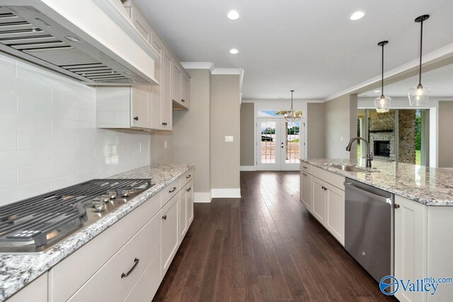 kitchen with dark wood-type flooring, a center island with sink, sink, stainless steel dishwasher, and a fireplace