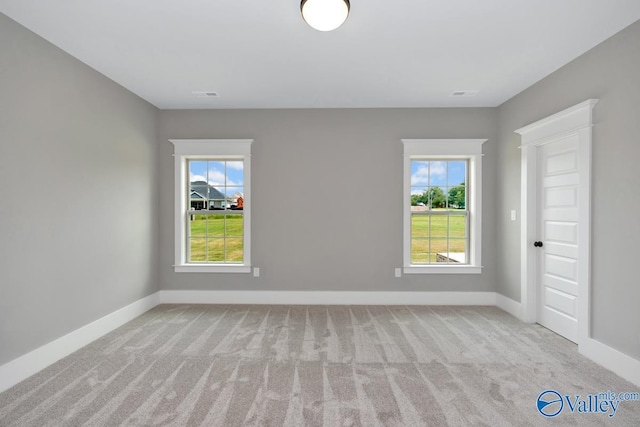 carpeted spare room with visible vents and baseboards