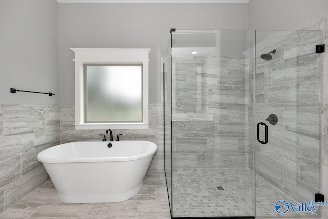 bathroom featuring a freestanding tub, tile walls, and a shower stall