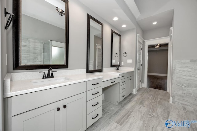 full bathroom with recessed lighting, vanity, and a walk in closet